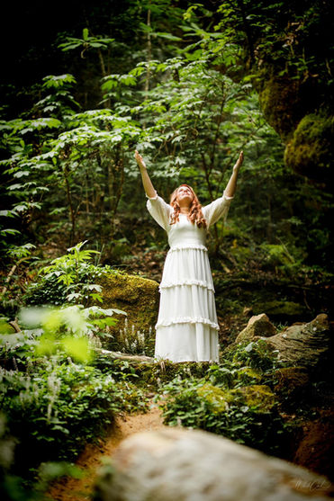 Loretta Jent lifting her hands in worship in the woods